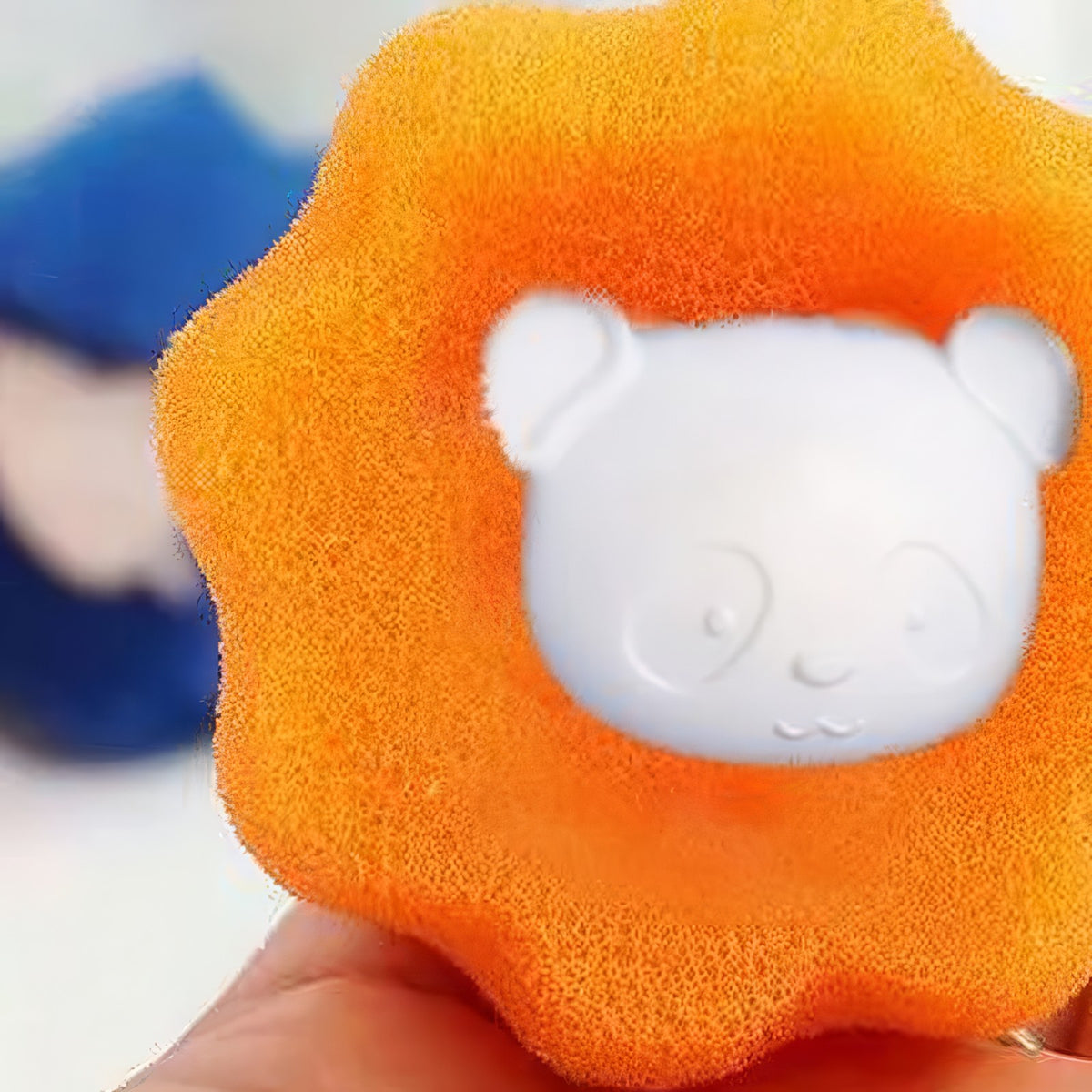 Close-up of an orange pet hair remover ball with its white bear-face center