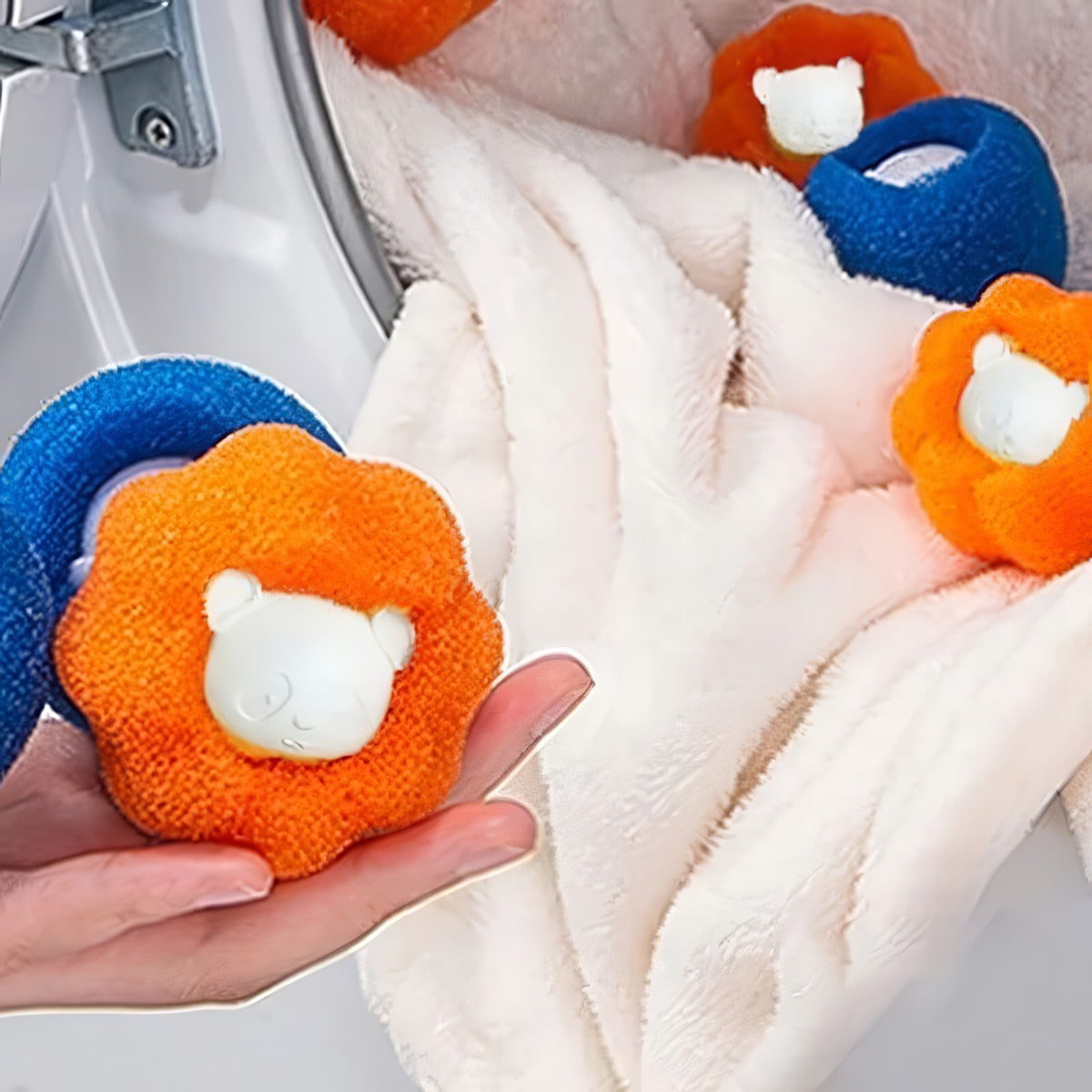 Hand holding blue and orange Furloop pet hair remover balls in front of a washing machine