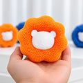 Hand holding an orange Furloop pet hair remover ball with a white bear face